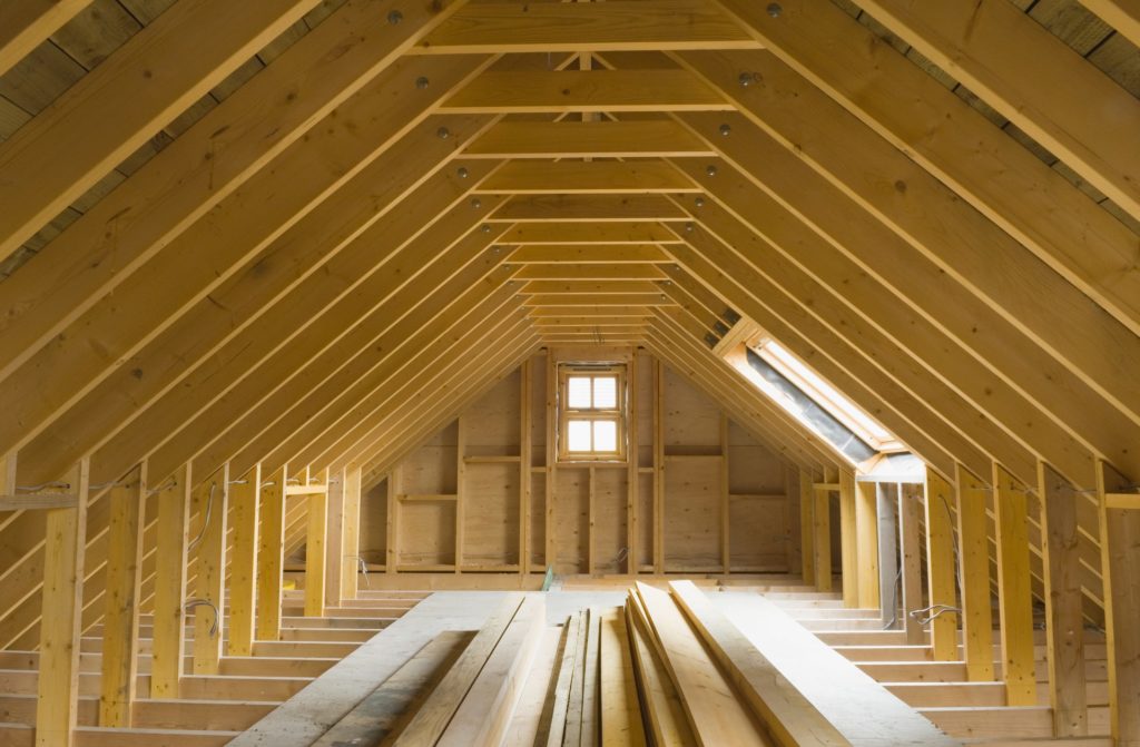 Combles sous une charpente en bois neuve, avec fenêtre de toit et planches de plancher