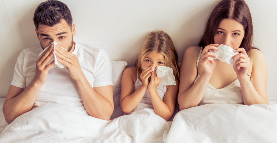 Famille au lit se mouchant, symptômes d’allergie respiratoire à la maison