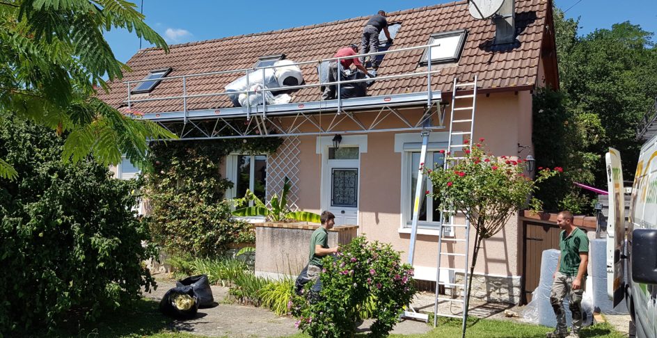 Isolation de toiture par l’extérieur : couvreurs sur un pan de tuiles ouvert, derrière un garde-corps